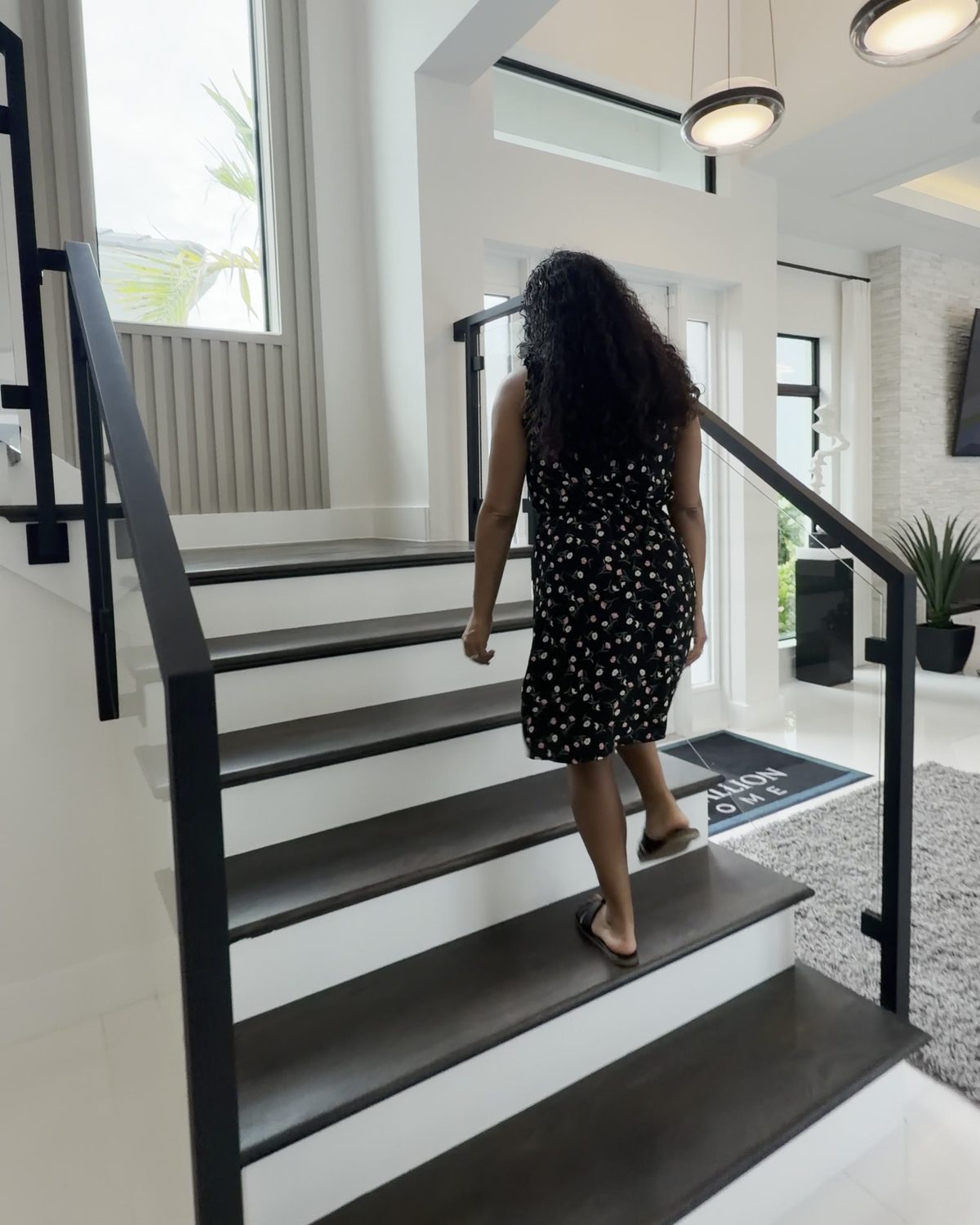 Sekina walking up the floating staircase in a two-story model home at Aqua.