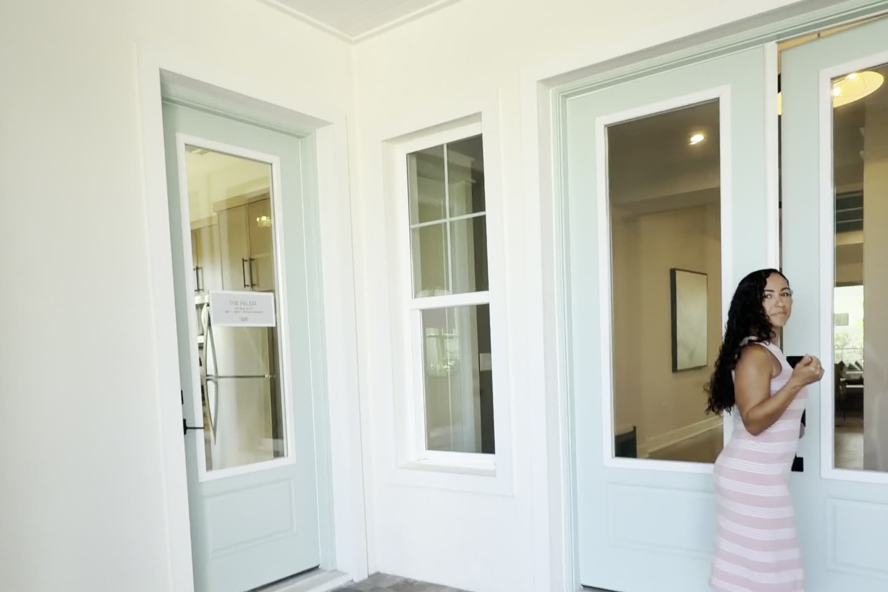 Sekina at the front door of the Cardel Palma model at SeaFlower, with the in-law suite's own private entrance door to the left.